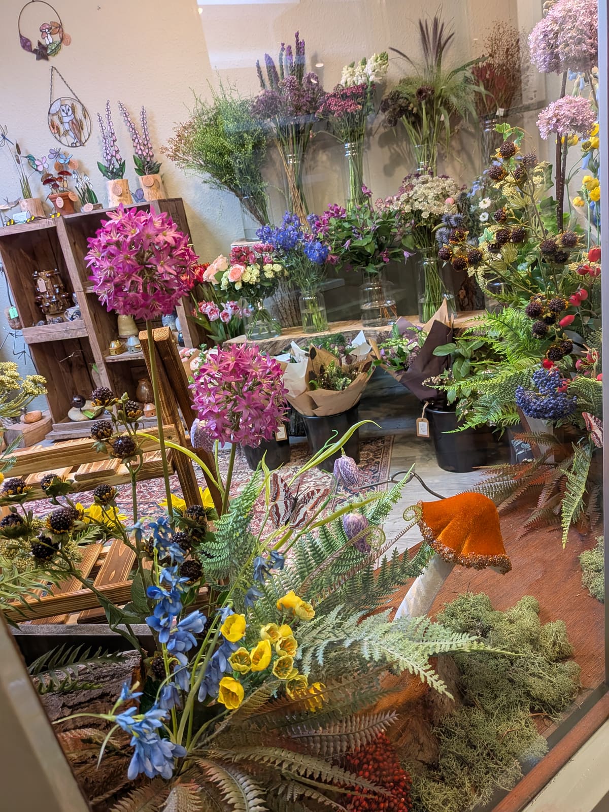 Inside the shop: buckets of seasonal stems, wrapped bouquets and handmade gifts on wooden crate shelves