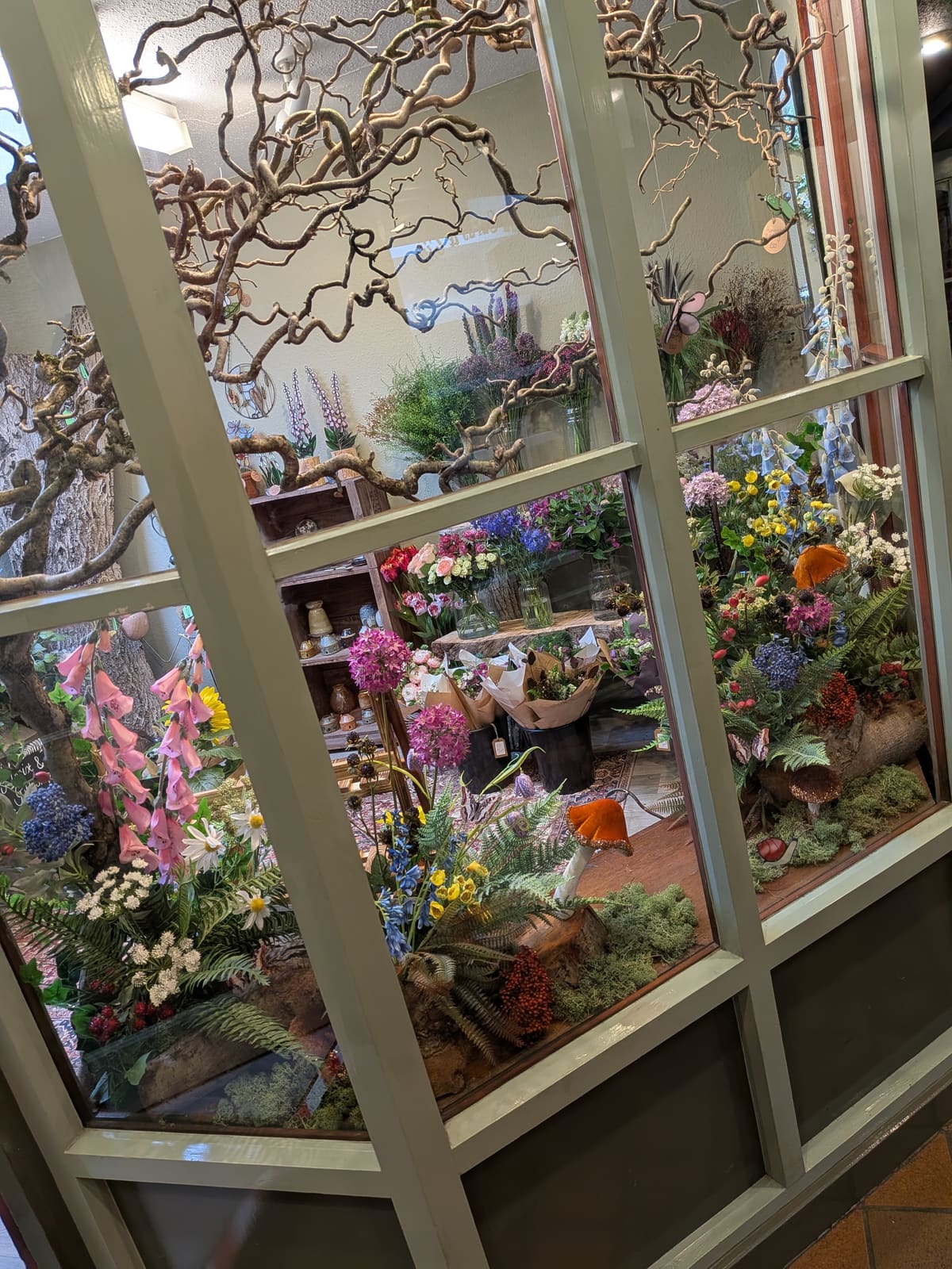The Bramble Hollow shop window in Bakewell, filled with foxgloves, twisted hazel branches, toadstools and wild flowers